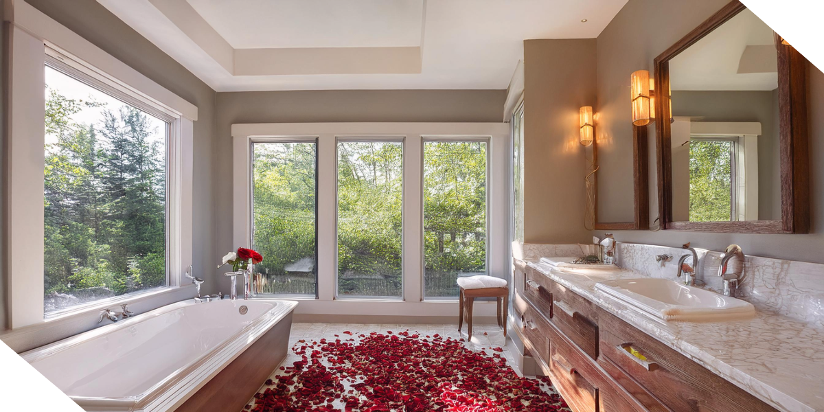 Renovated bathroom with large windows, a soaking tub, and modern fixtures, enhanced by romantic rose petals.