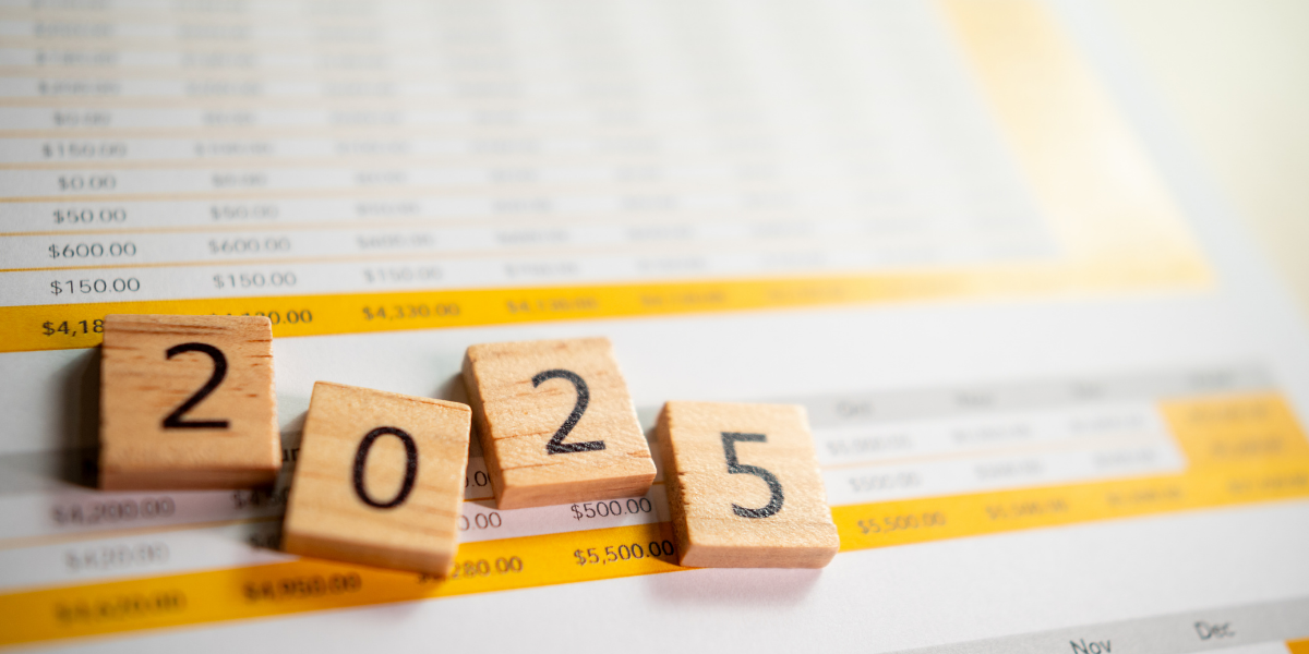 Wooden blocks displaying '2025' placed on a financial spreadsheet with yellow and white highlights, symbolizing financial planning and projections for the upcoming year.