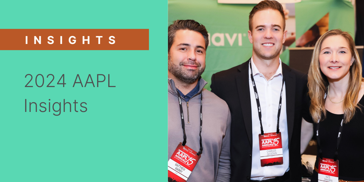 Three Kiavi employees smile at the camera at the 2024 AAPL Annual event, wearing conference badges. A Kiavi-branded backdrop is visible in the background.