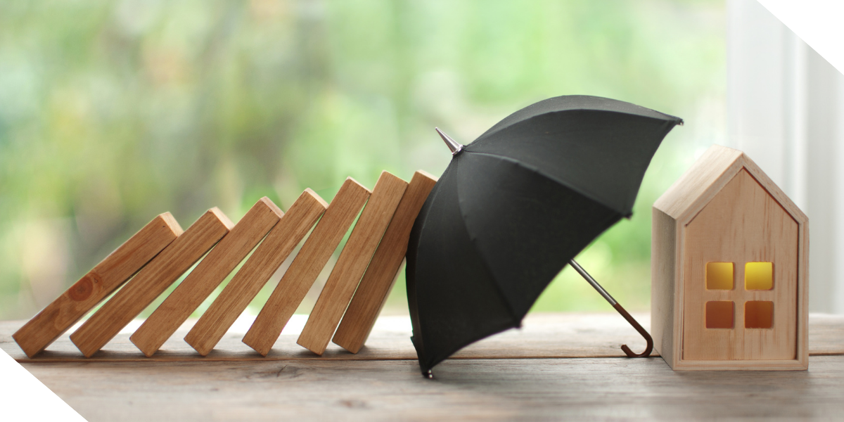 Black umbrella protecting a small wooden house from falling blocks, symbolizing home insurance or financial protection.